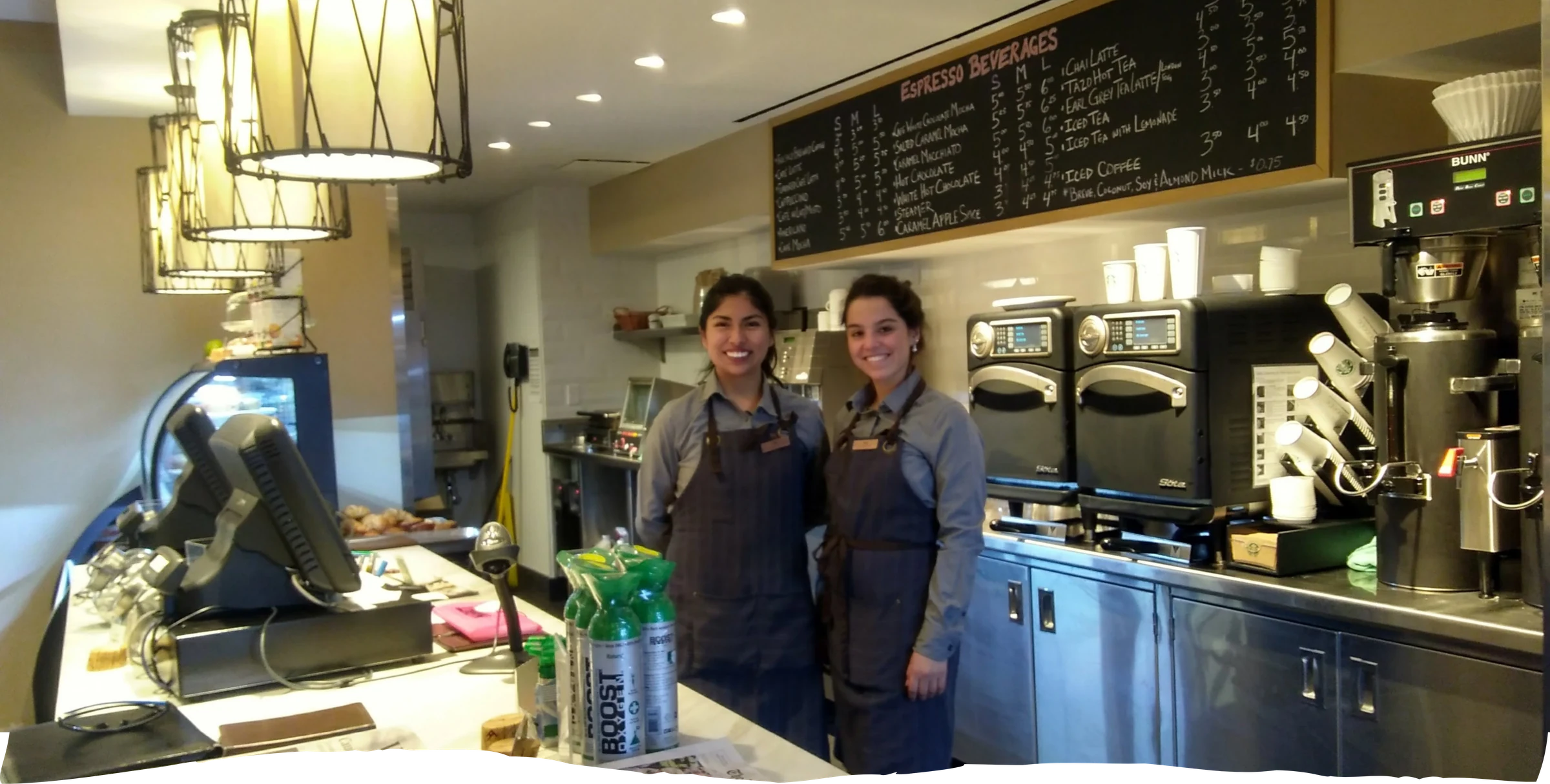 Dos participantes con delantal gris trabajando en una cafetería